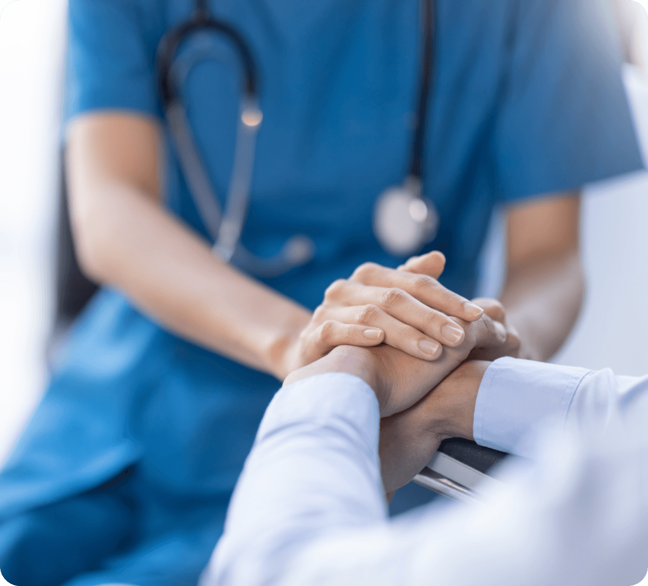 Medical professional in scrubs comforting patient by holding hands