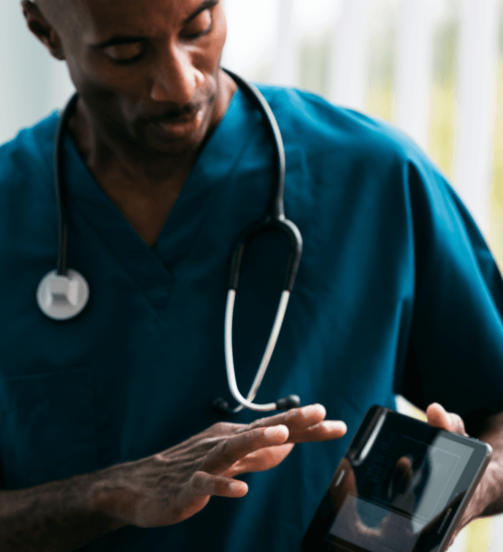 Medical professional in scrubs with a stethoscope holding a smartphone