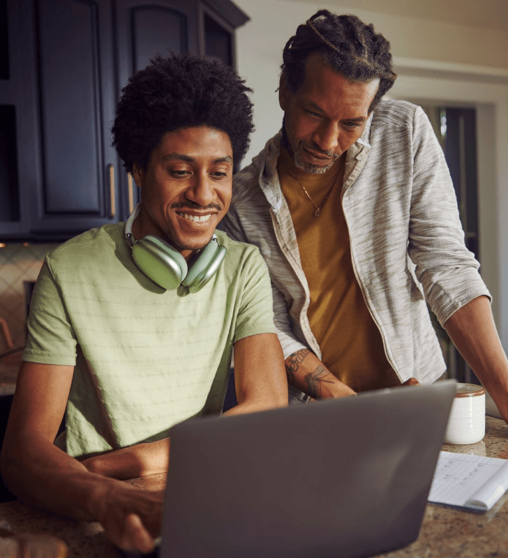 Two people at a kitchen counter with one using a laptop and the other standing